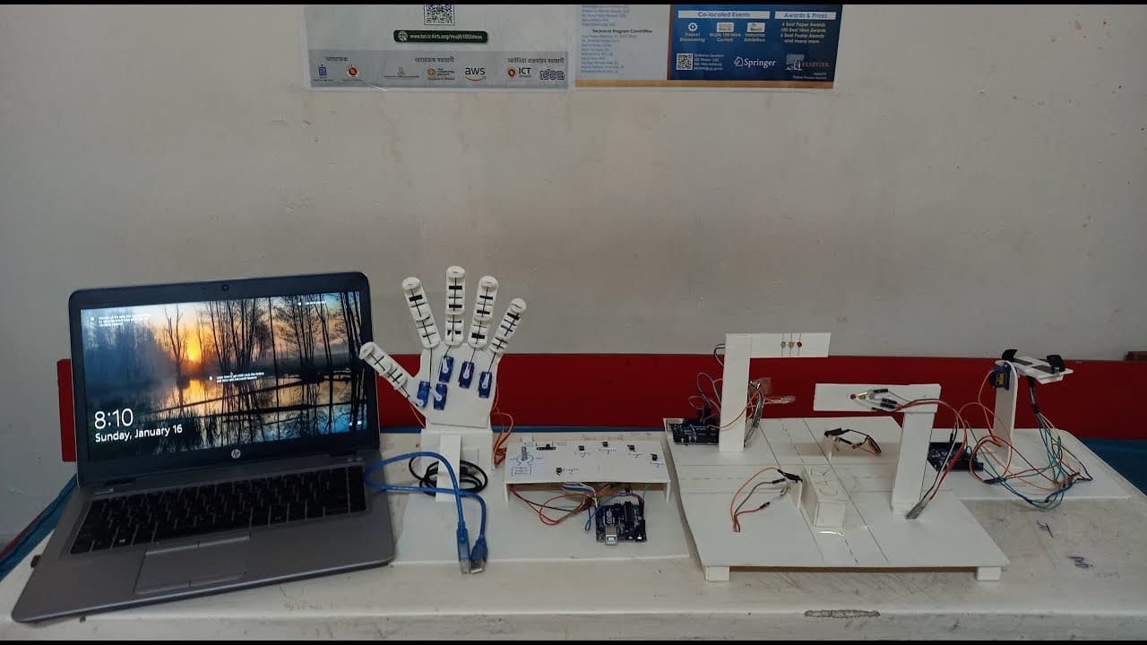 The build on a bench: a five-fingered servo hand and a jointed arm cut from white board, wired back to Arduino boards and a laptop.
